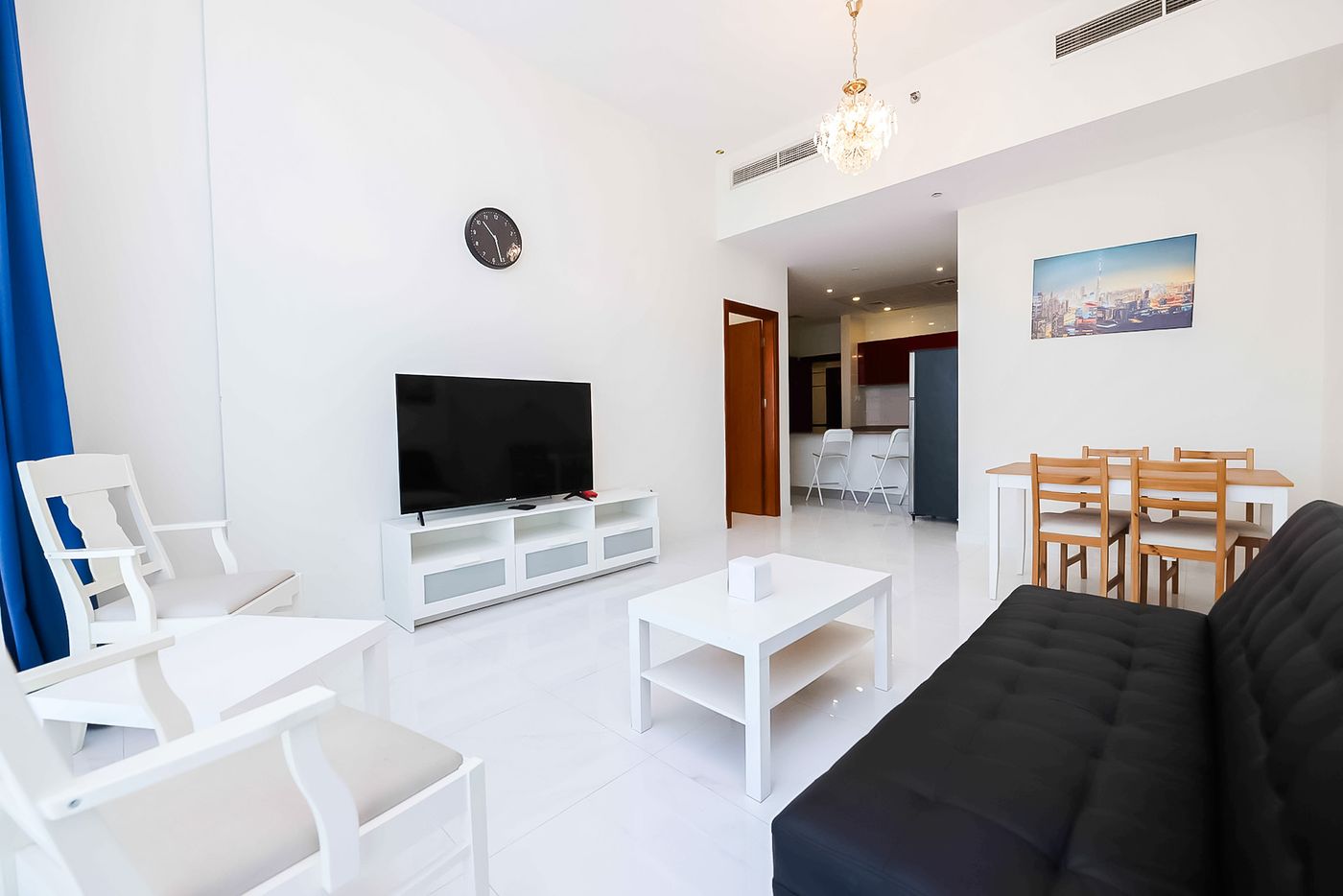 One-bedroom living room with a sofa bed, a TV, a dining table and an open kitchen
