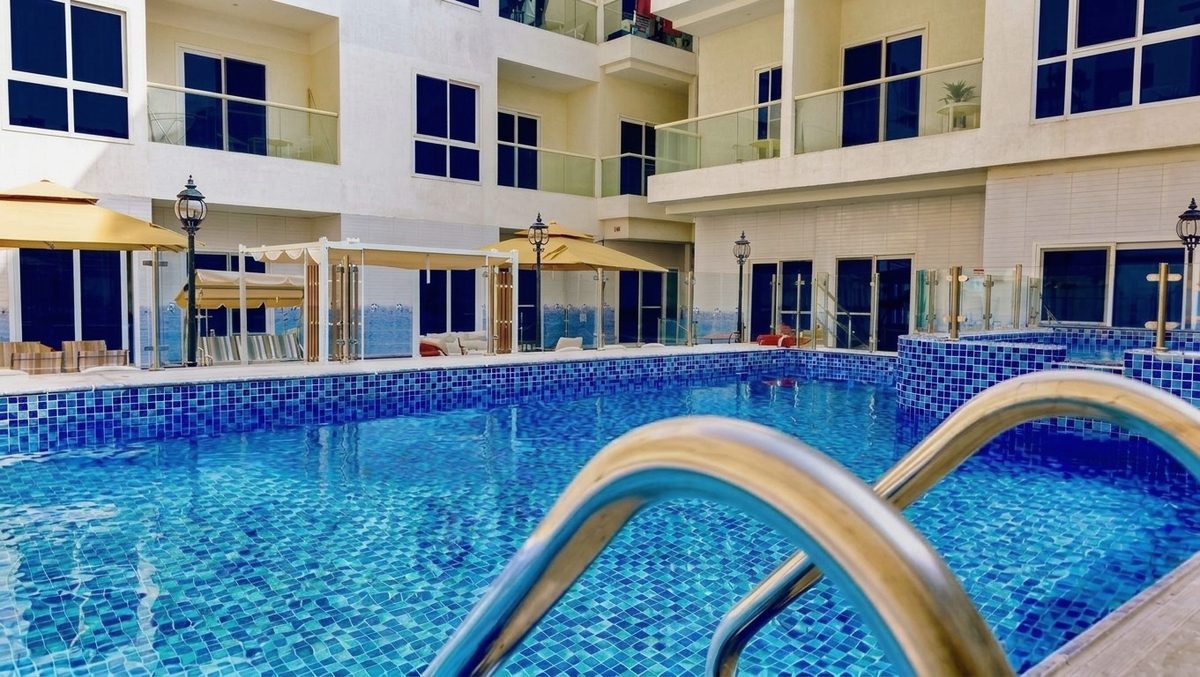 Pool deck with canopies and umbrellas beside the apartment building