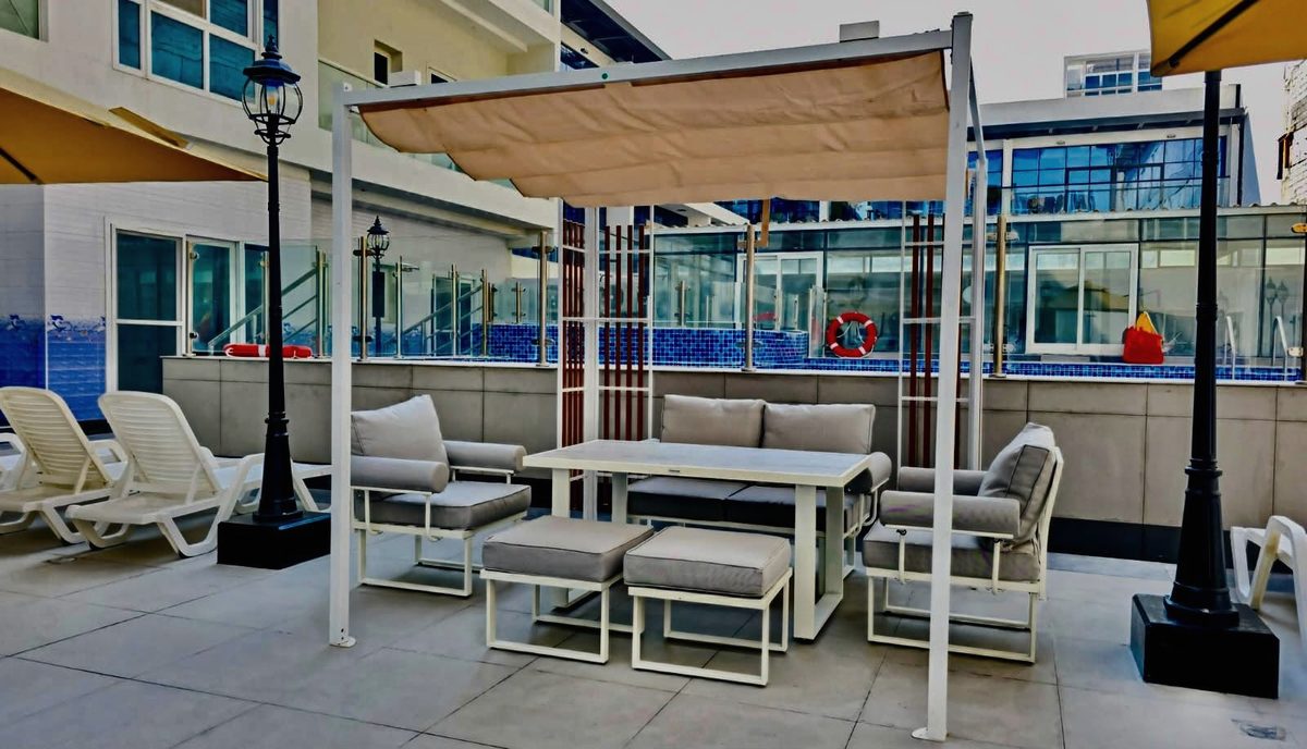 Shaded outdoor lounge seating with a table and sun loungers beside the pool